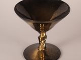 black and gold glass bowl with a twisted handle on a pedestal