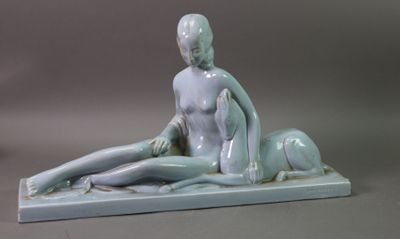 a statue of a woman sitting on the ground next to a dog