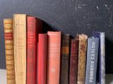 de nombreux livres anciens alignés sur une étagère près d'un mur noir