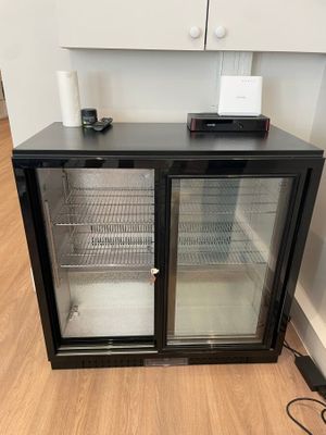 un petit réfrigérateur posé au sol, muni de deux portes en verre
