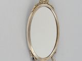un miroir ovale fixé au mur, avec un cadre doré