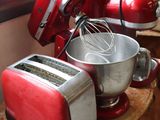 a red mixer and a red toaster on a wooden table