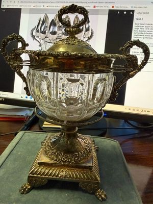 un vase en verre posé sur une table, avec un ordinateur en arrière-plan