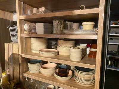 many plates and bowls on the shelves in the kitchen
