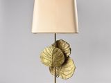 a gold leaf lamp with a beige shade on a white table