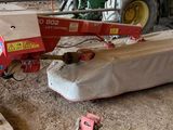 un tracteur garé dans une grange, à côté d'un tas de bois