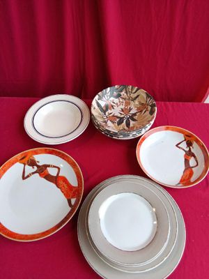 several plates and bowls are sitting on a red table cloth