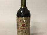 an old bottle of wine sitting on top of a white table