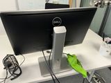 a computer monitor sitting on a desk with a green leaf on it
