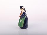 a figurine of a woman holding a green bag