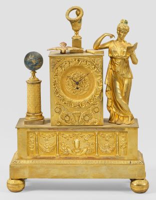 a gold clock with a statue on top of it