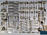 un grand nombre de cuillères et de fourchettes disposées sur une table