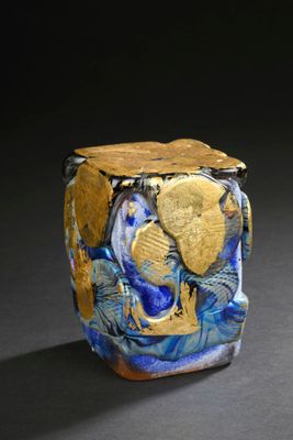 a blue and gold vase sitting on a black surface