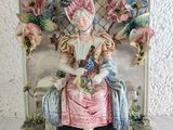 a figurine of a woman sitting on a bench