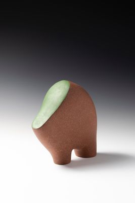 un petit objet marron avec une partie supérieure verte, posé sur une surface blanche