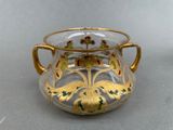a glass vase with a gold decoration on it
