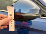 a hand that is holding a ruler in front of a car