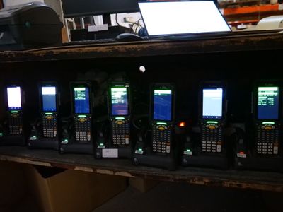 many cell phones lined up on a shelf in a room