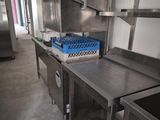 a large stainless steel kitchen with a sink and a refrigerator