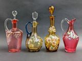 four different colored glass vases sitting next to each other on a gray surface