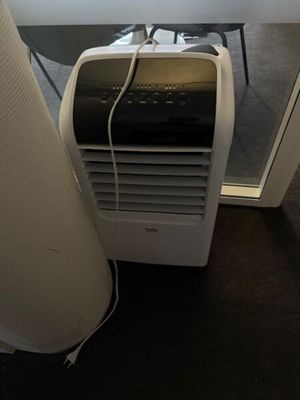 a small air conditioner sitting on the floor next to a window