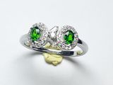 un gros plan d'une bague sertie d'un diamant vert et blanc posée sur une surface blanche