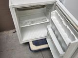 a small white refrigerator with its door open on the floor