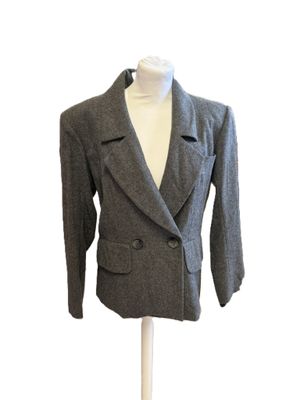 veste en laine grise posée sur un socle de mannequin