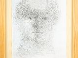 une image représentant le dessin d'un visage d'homme dans un cadre en bois
