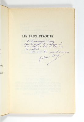 un livre ouvert, dont une page est écrite à la main, posé sur une table
