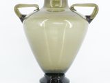 a green vase with two handles on a black base