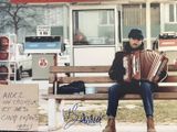 un homme assis sur un banc avec un accordéon