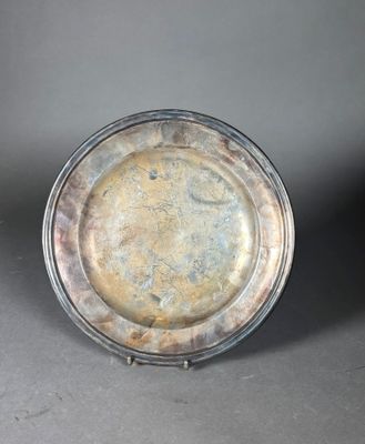 un plat en argent ancien posé sur une surface grise