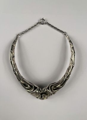gros plan d'un collier en argent sur une surface blanche