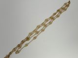 a close up of a gold bracelet with a chain on a white surface