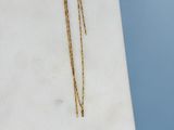 un gros plan d'un collier en or posé sur une surface en marbre
