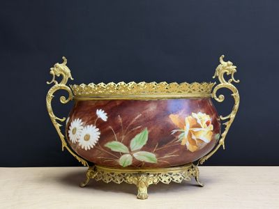 un vase avec des fleurs peintes dessus, posé sur une table