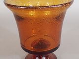 un vase en verre brun avec un socle brun posé sur une table