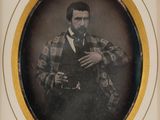 an old photo of a man in a suit and tie holding a pipe