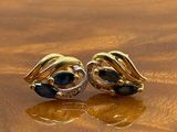pair of black and gold earrings on a wooden surface