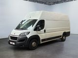 La camionnette blanche est garée dans une grande pièce au sol noir
