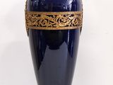 un vase bleu orné de motifs dorés sur un fond blanc