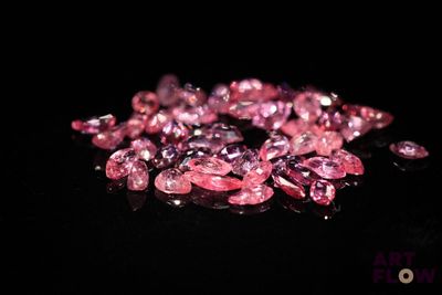 some pink diamonds on a black surface with a black background