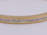 a close up of a gold and diamond bracelet on a white surface