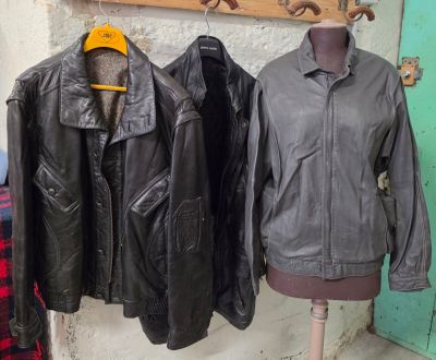 trois vestes en cuir accrochées au mur à côté d'un mannequin
