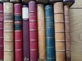 many old books lined up on a wooden shelf