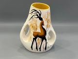 un petit vase orné d'un cerf, posé sur une table