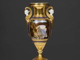 un vase en or orné d'une peinture, posé sur une table