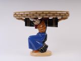 une figurine de femme portant un panier sur la tête