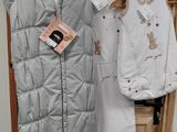 trois vêtements pour bébé suspendus à un portant dans un magasin